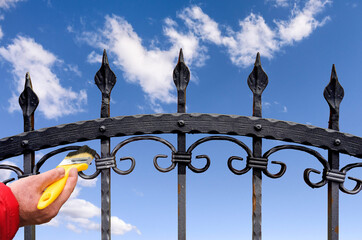 hand with brush painting iron fence
