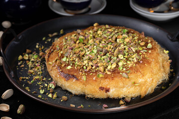 Kanafe arabic dessert with green almonds. Traditional arabian Kanafe cake with Kadaif hair noodels with soft focus. 
Eastern cookies beautifully served on metal plate. 
