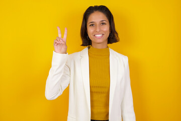 Young caucasian woman standing against gray wall showing and pointing up with fingers number two while smiling confident and happy.