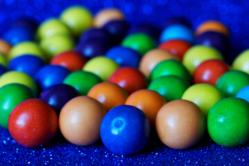 Fototapeta na wymiar Round multicolored candy or gum lies on a sparkling blue surface. Festive mood. Close-up.