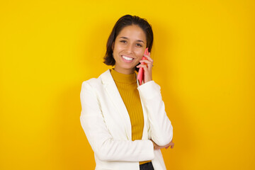 Portrait of a smiling young casual brunette woman talking on mobile phone isolated over white...