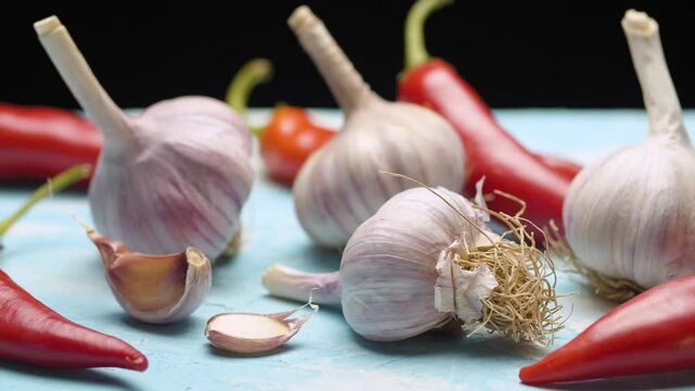 Close up fresh raw garlic and spicy pepper on the table on black background. Dolly shot