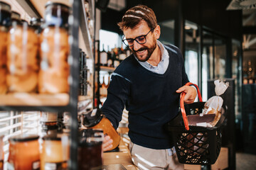 Handsome middle age man buying some healthy food and drink in modern supermarket or grocery store. Lifestyle and consumerism concept.