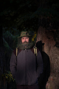 Portrait Of An Adult Man In A Hat With A Mosquito Net In Forest  In Summer