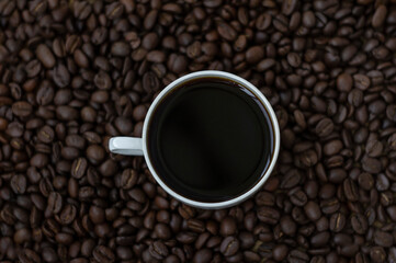 Hot black coffee in white cup on the coffee beans background