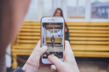 amiga tomando una foto con el móvil de una mujer junto a un banco amarillo en tarde de invierno