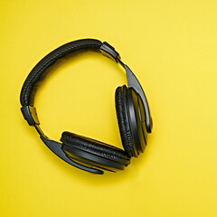 Large, black headphones lie on a colored background. Device for individual listening to music.