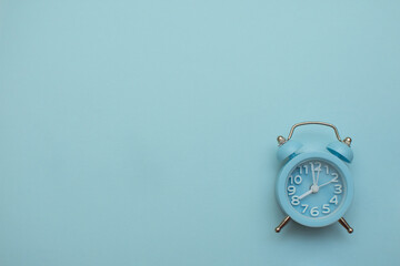 blue clock alarm clock on a light blue background, place for an inscription