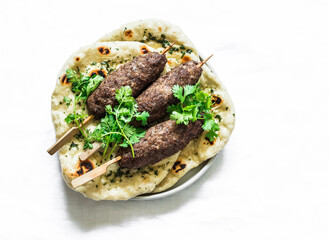 Grilled kebab and garlic herb flatbread naan on a light background, top view. Delicious tapas