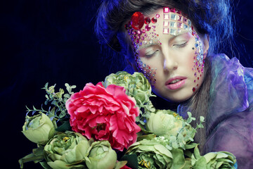 young woman with creative make up holding flowers