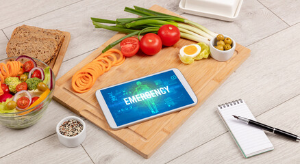 EMERGENCY concept in tablet with fruits, top view
