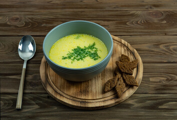 Appetizing cheese soup in a gray plate on a wooden background.