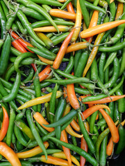 Green hot chili peppers, closeup view and for sale in market