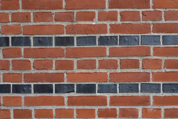 Old rural brickwork facade with red and black bricks - background