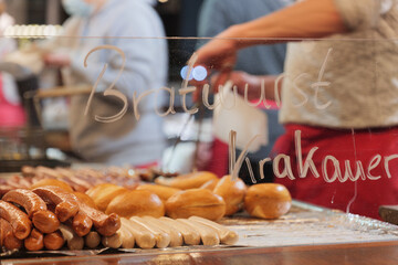 Selective focus, heap of grilling sausages on barbecue grill beside Brötchen, German style bread, at a stall of Christmas market in winter season in Germany.