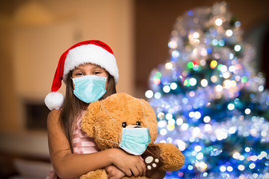 Girl and teddy bear wearing a mask, Christmas coronavirus and pandemic concept
