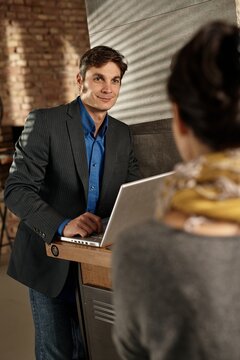 Businessman using laptop smiling at female colleague.