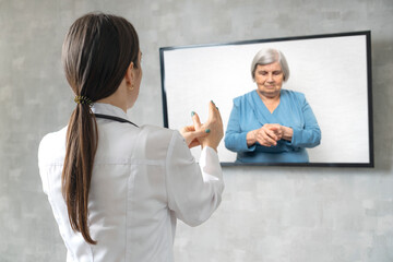 Online medical consultation. Remote medicine during quarantine. Female doctor consults an elderly woman on video conference about the painful palms.