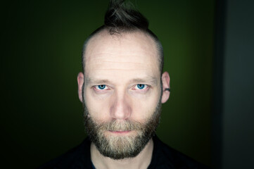 Fototapeta premium Man with beard and mohawk looks seriously at the camera.