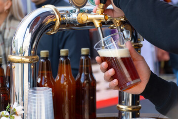 Barman hands pouring a beer in a plastic glass 