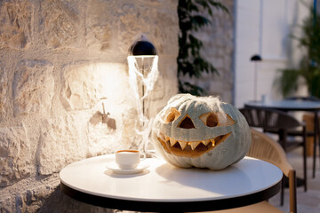 Halloween pumpkin. Table with coffee and jack o lantern pumpkin. Holiday interior and decoration in cafe indoors.