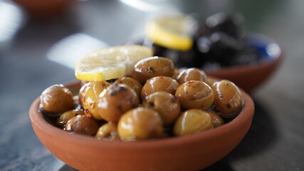 Green and black olives with lemon in the plate.