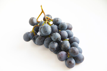 Black grapes, large fresh fruits with green leaves on a white background