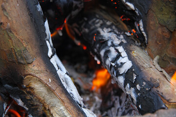Glowing embers in hot red color, abstract background. The hot embers of burning wood log fire. Firewood burning on grill. Texture fire bonfire embers.