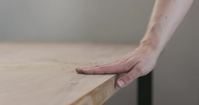 Slow motion slide orbit shot of man hand checking sanded black walnut wood table