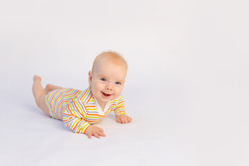 small smiling baby girl 6 months old lies on a white isolated background in a bright bodysuit,...