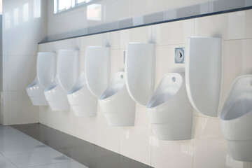 Row of white ceramic urinals for men in restroom.