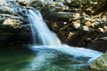 small mountain waterfall among the rocks, the water is blurred in motion