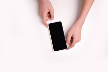 Hands are holding a mobile phone on a white background isolated. View from above
