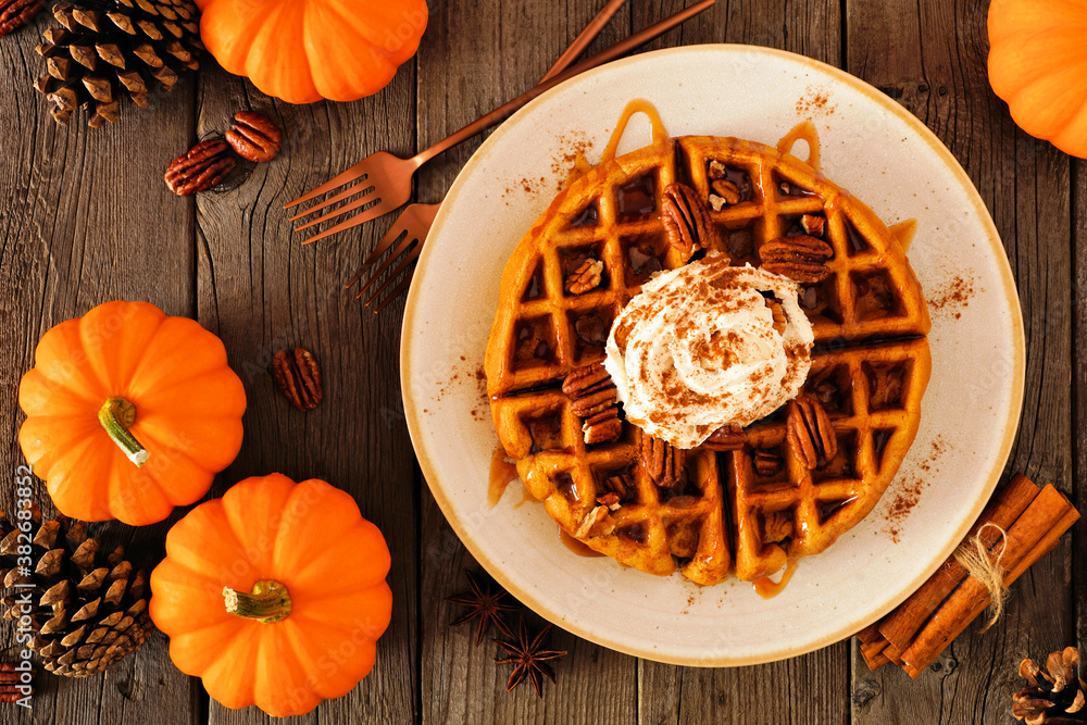 Poster pumpkin spice waffle with whipped topping, caramel and pecans. top view table scene on a dark wood b