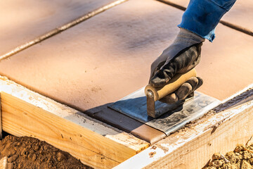 Construction Worker Using Hand Groover On Wet Cement Forming Coping Around New Pool