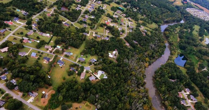 The Haw River in Graham, NC is seen as we fly over. On both sides of the river, we see development encroaching on the river. A bridge crosses the river. A power distribution site is seen. We bank left