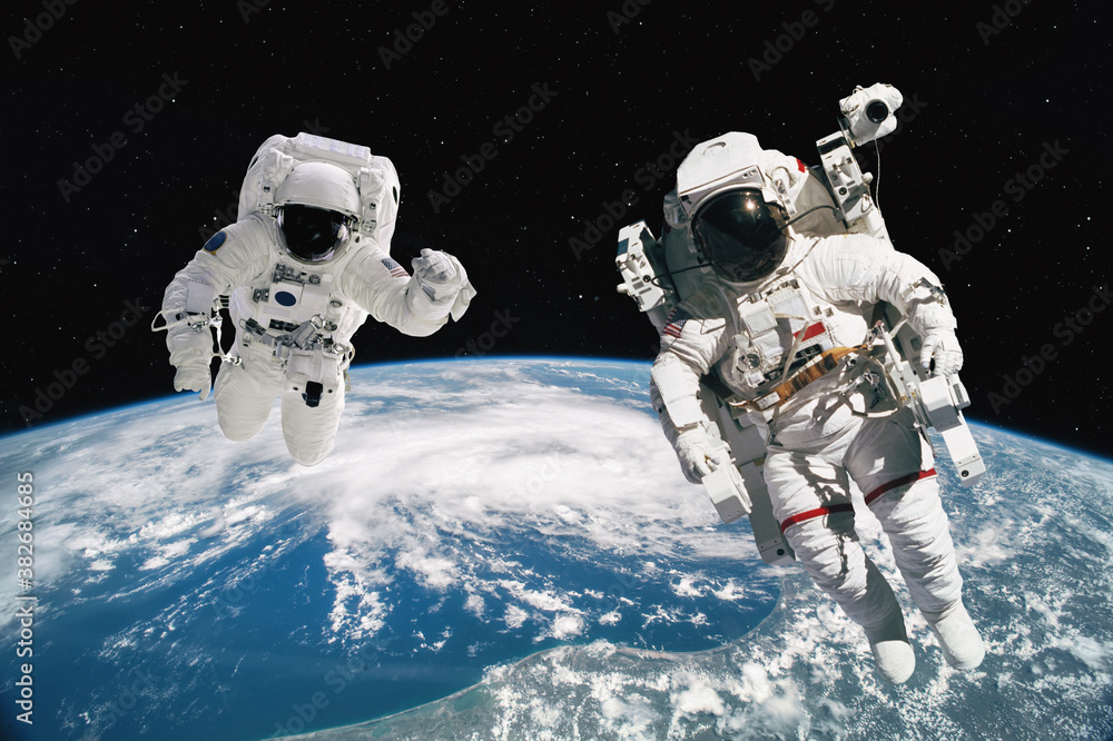 Poster two astronauts walking in space with earth background. elements of this image furnished by nasa