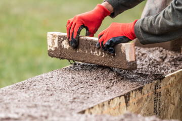 Construction Worker Leveling Wet Cement Into Wood Framing