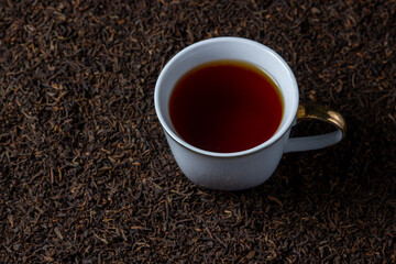 Leaf tea. a lot of loose tea. A cup of tea stands on loose tea