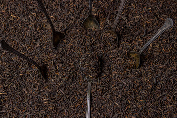 Leaf tea. a lot of loose tea. Teaspoons sticking out of a pile of loose tea