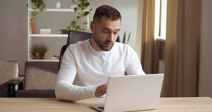 Stressed young businessman sitting at desk typing use pc, feels stress gesticulating with angry face expression, unsuccessful results of work unsaved information, lost net connection, failure concept