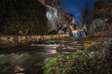 Trillo nightscape with a waterfall and the river crossing the center of the village at night, Guadalajara, Spain.