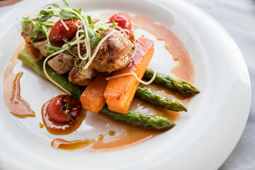 Roasted duck in slices with wine sauce, served with cherry tomatoes, sliced carrots and asparagus.Grilled steaks with asparagus and carrots served at the restaurant.Juicy duck breast