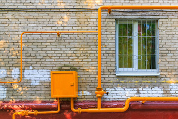 Yellow pipes of gas hub on the facade of the residential building