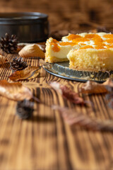 Cheesecake oder Käsekuchen mit fruchtigen orangen Mandarinen auf einem Tisch aus Holz im Herbst mit Laubblättern