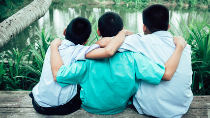Back view of three students friends hugging with love.Concept of best  friendship