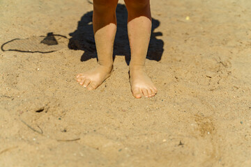 child's feet covered with sand on the beach. summer vacation concept