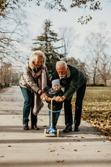 Happy good looking senior couple husband and wife walking and playing with their adorable grandson...