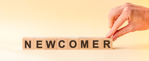 Woman made word NEWCOMER with wood blocks