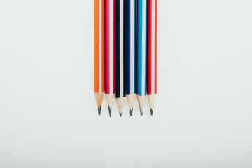 Multicolored wooden graphite pencils on light background. Top view.
